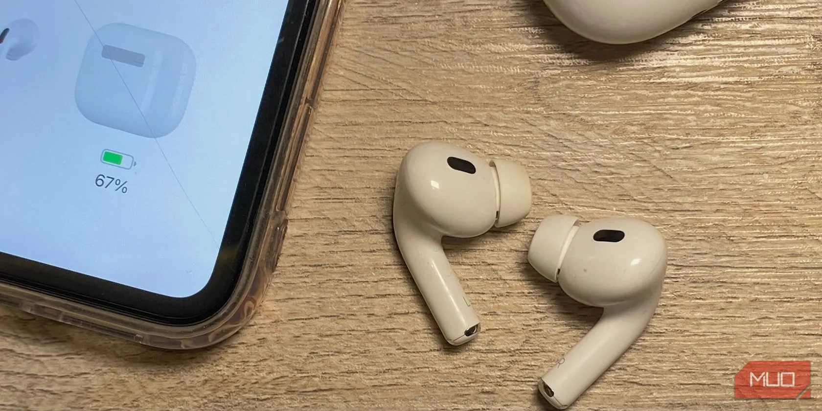 AirPods đời thường với thân dài và thân ngắn đặt cạnh iPhone trên bàn gỗ, minh họa sự khác biệt về thiết kế thân tai nghe.