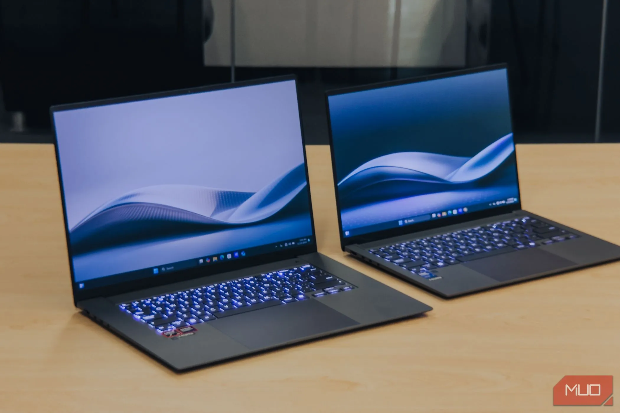 ASUS Zenbook S 16 OLED đặt cạnh Zenbook S14 trên bàn gỗ