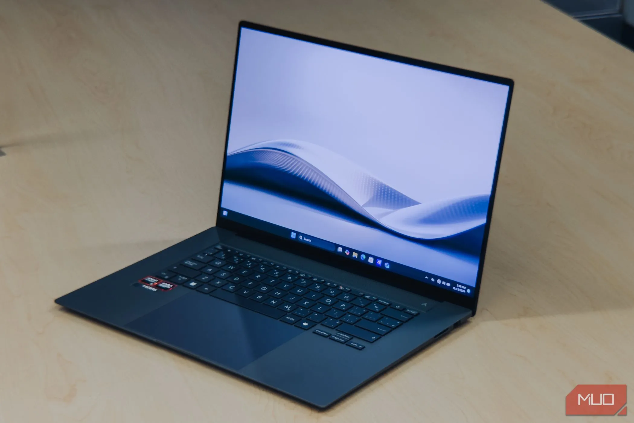 ASUS Zenbook S 16 OLED nghiêng trên bàn gỗ với màn hình đang bật