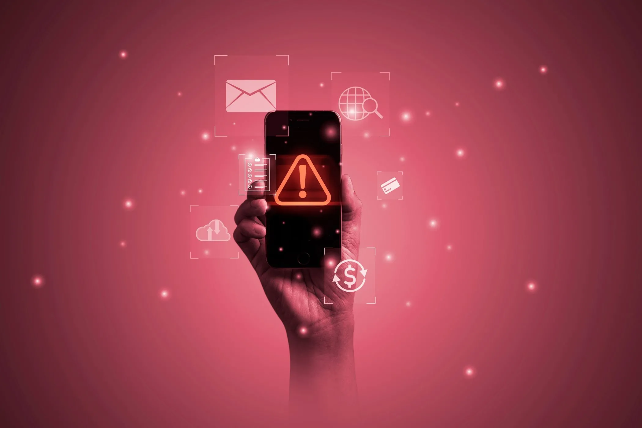 Bàn tay cầm điện thoại với màn hình hiển thị biểu tượng cảnh báo malware