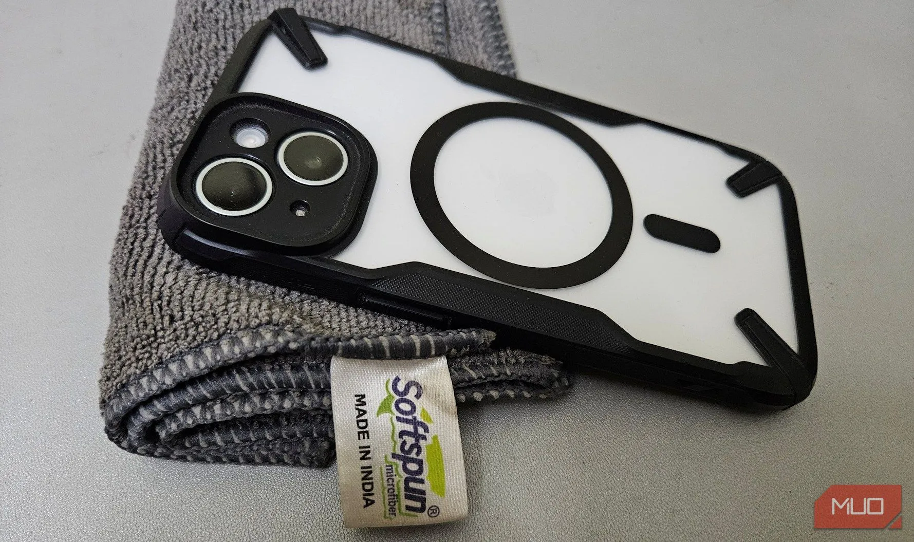 Bàn tay đang dùng khăn microfiber chuyên dụng lau sạch ống kính camera điện thoại, chuẩn bị cho buổi chụp ảnh đêm rõ nét