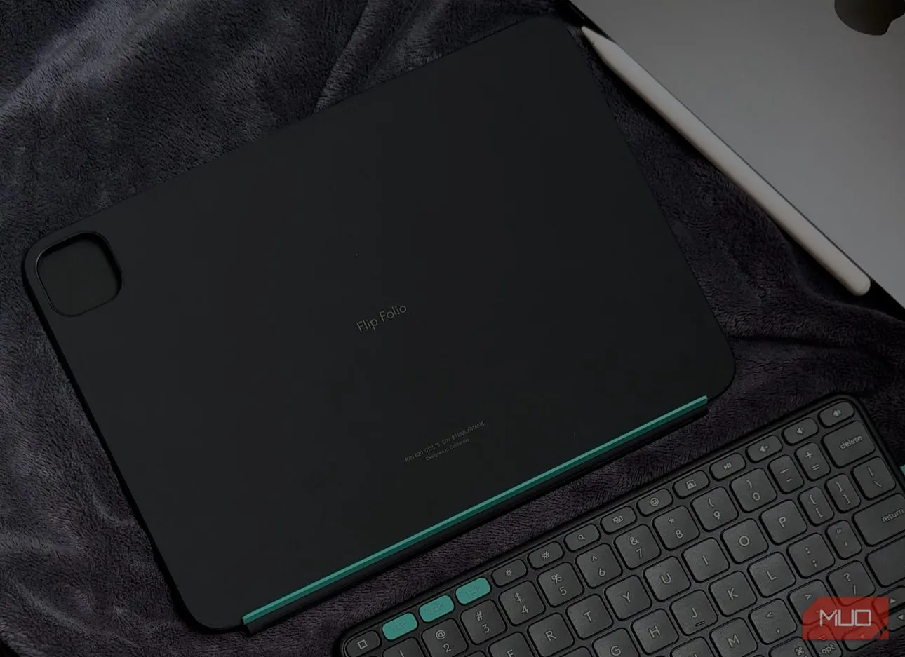 Bao da kiêm bàn phím Logitech Flip Folio màu xám đặt cạnh iPad trên chăn, cho thấy khả năng sử dụng thoải mái ở nhiều môi trường khác nhau.
