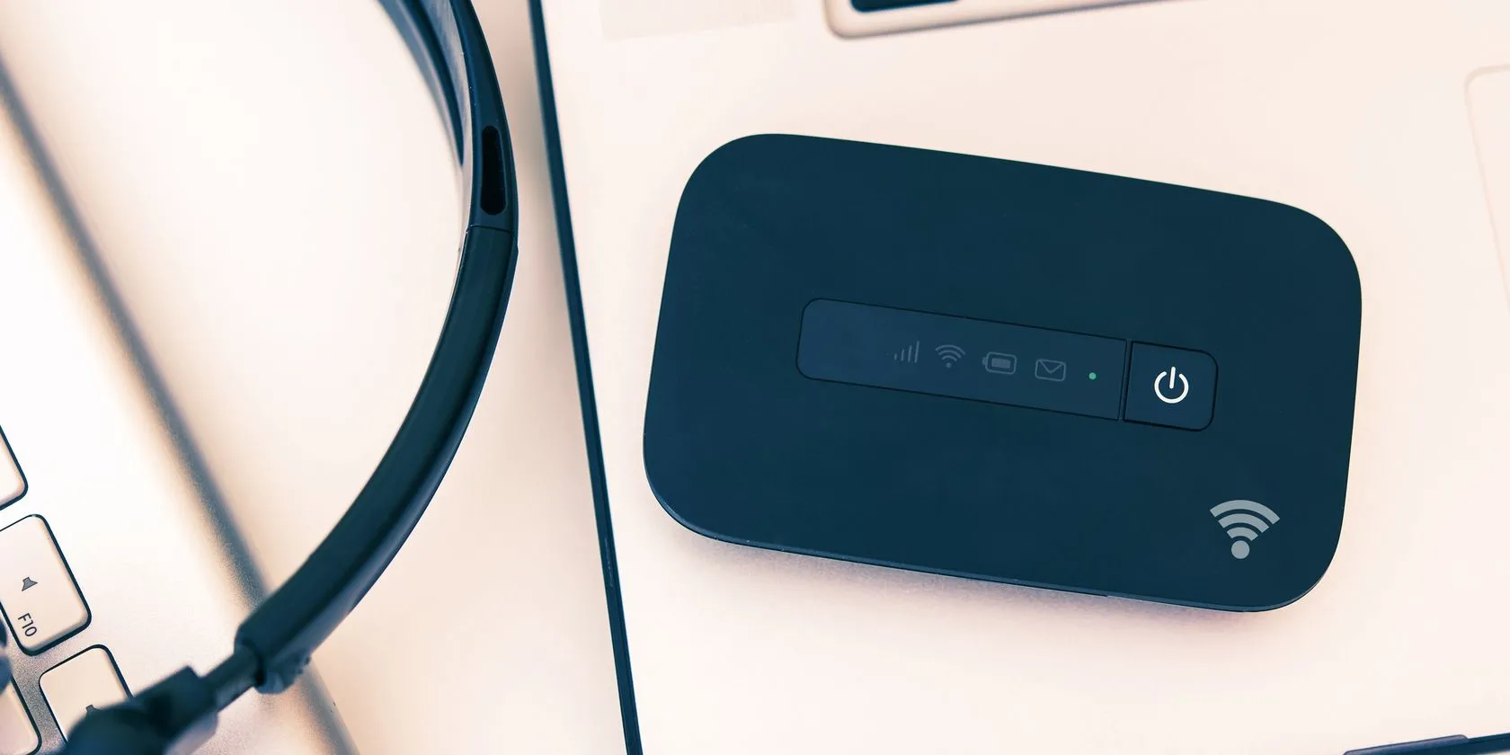 Bộ phát Wi-Fi di động được đặt cạnh laptop, đảm bảo kết nối internet ổn định khi làm việc từ quán cà phê