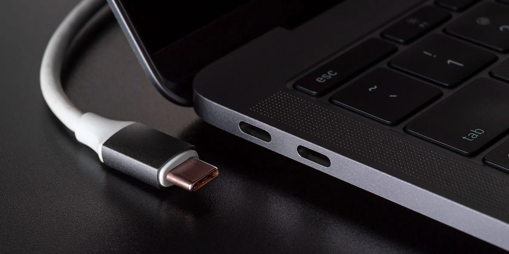 Cổng kết nối USB-C trên laptop với cáp USB-C đang được cắm, tượng trưng cho việc sạc nhanh khi laptop ở chế độ ngủ