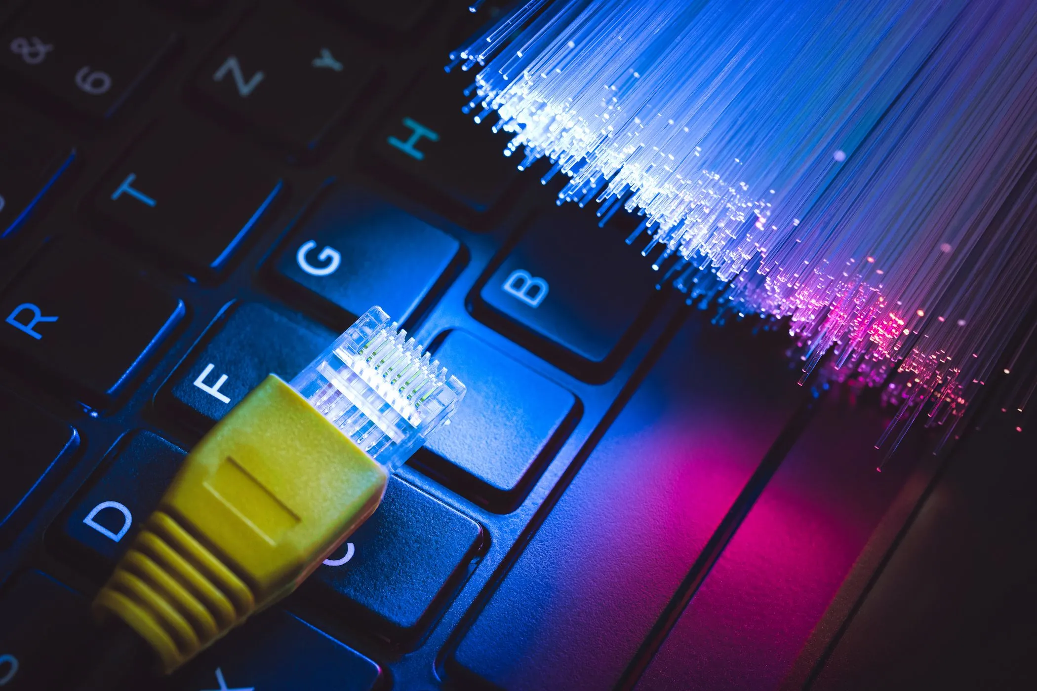 Đầu nối cáp Ethernet và cáp quang đặt trên bàn phím laptop, tượng trưng cho kết nối mạng có dây và không dây