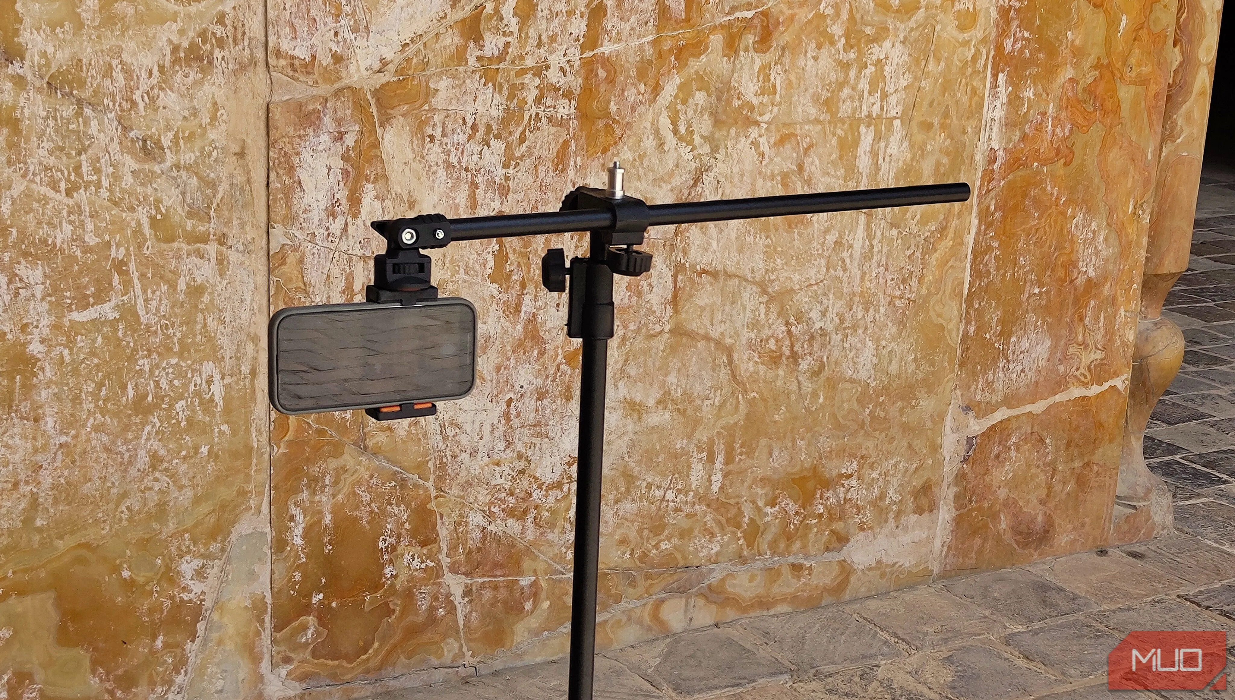 Điện thoại gắn trên tripod hướng về phía bức tường, minh họa việc chọn chủ thể cao khi chụp panorama dọc