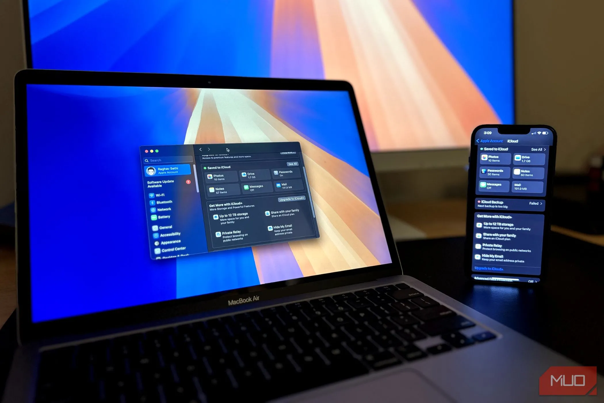 Điện thoại iPhone đặt cạnh MacBook đang hiển thị menu iCloud, minh họa việc sao lưu iPhone qua máy tính
