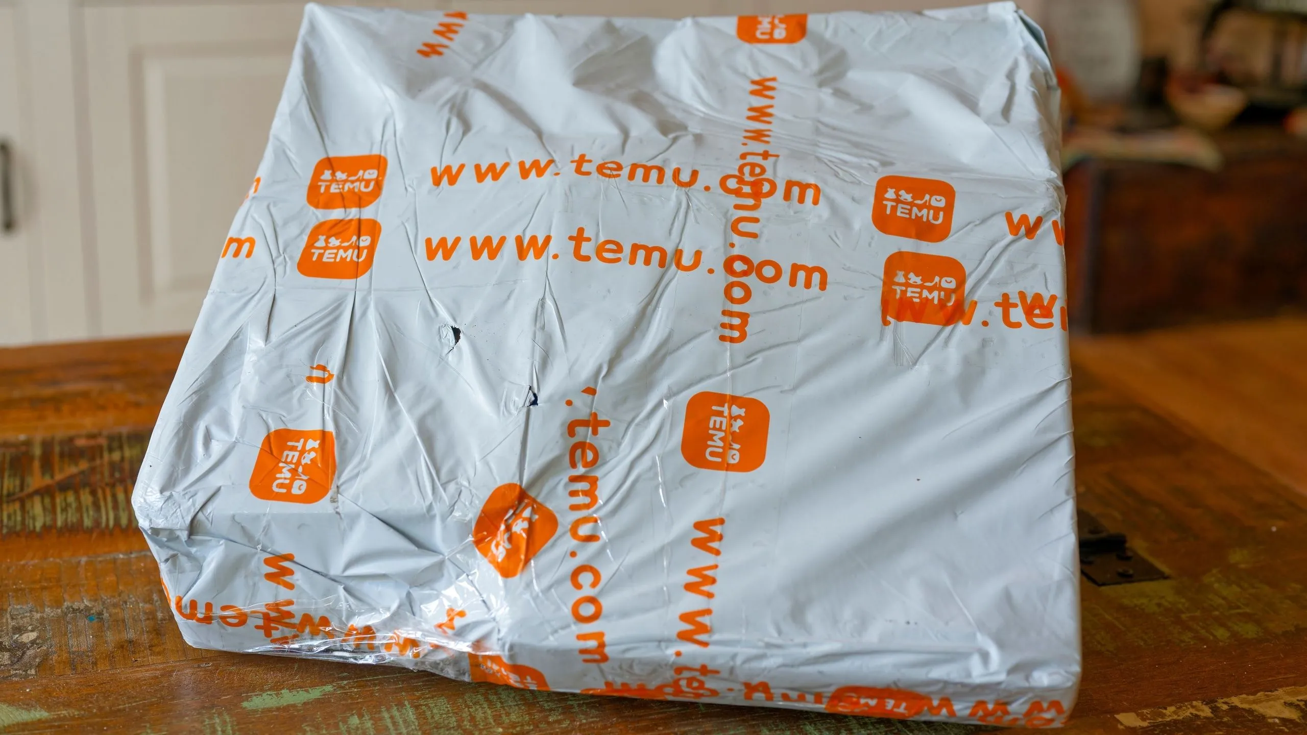 Gói hàng Temu trên bàn làm việc, tượng trưng cho những thay đổi về giá cả và chính sách vận chuyển sản phẩm công nghệ