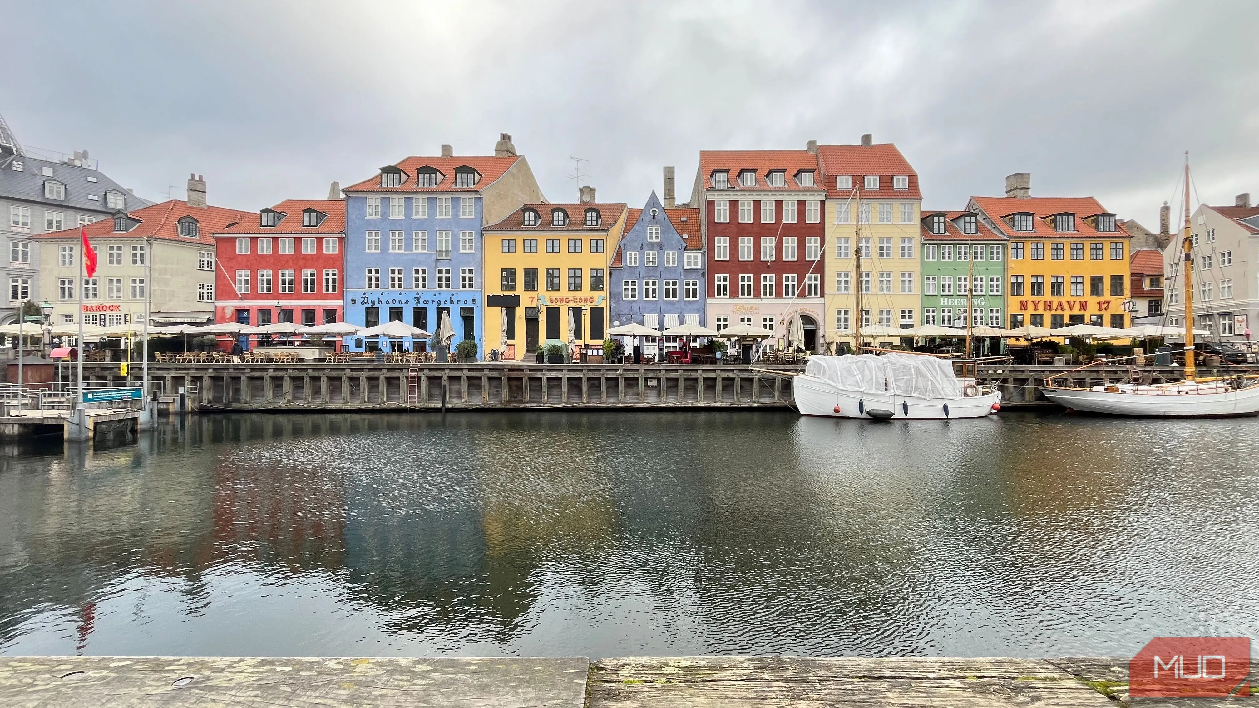 Kênh đào Nyhavn với các ngôi nhà nhiều màu sắc phản chiếu trên mặt nước dưới bầu trời u ám