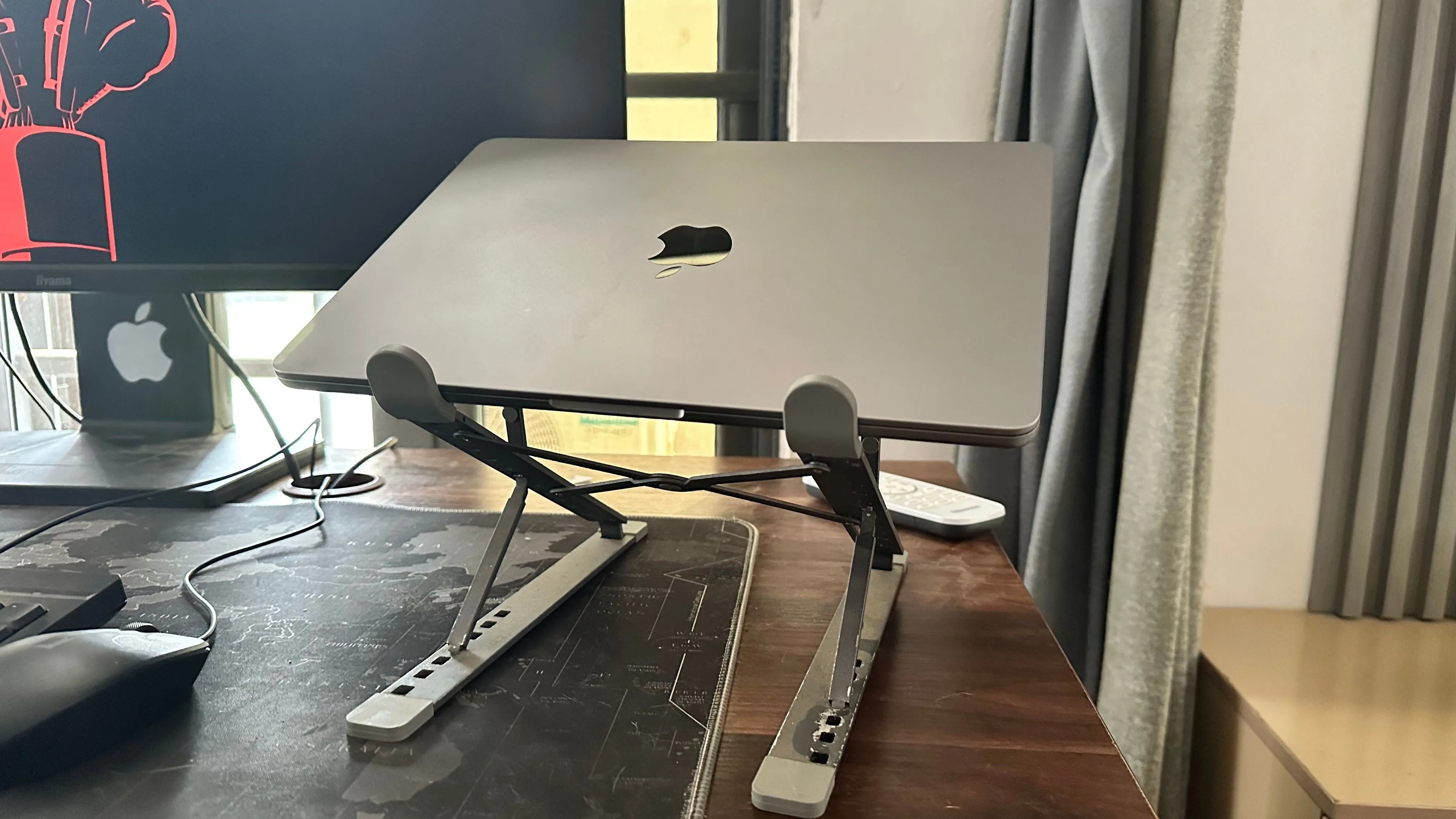 MacBook đặt trên đế tản nhiệt cạnh màn hình ngoài, minh họa cách tối ưu tản nhiệt khi dùng laptop với màn hình rời.