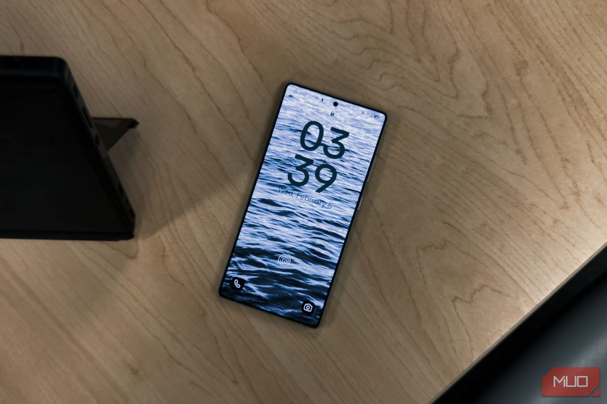 Màn hình khóa của điện thoại Samsung Galaxy S25 Ultra với đồng hồ hiển thị trên nền bàn gỗ, minh họa cho sự cạnh tranh về phần cứng giữa Android và Apple.