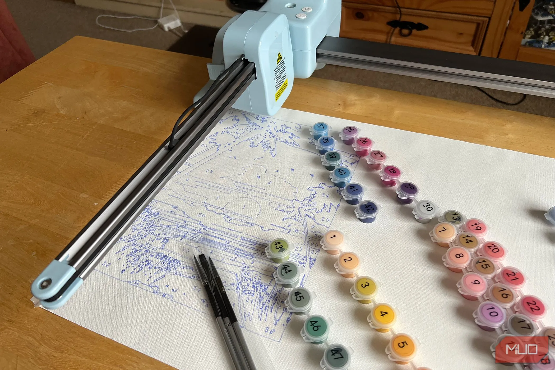 Máy LOKLiK iPaint đang vẽ cảnh hoàng hôn cùng các lọ sơn được đánh số.