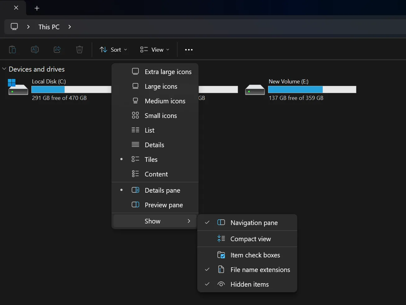 Menu View trong File Explorer hiển thị tùy chọn &quot;File name extensions&quot; được kích hoạt, phía sau là các phân vùng ổ đĩa.