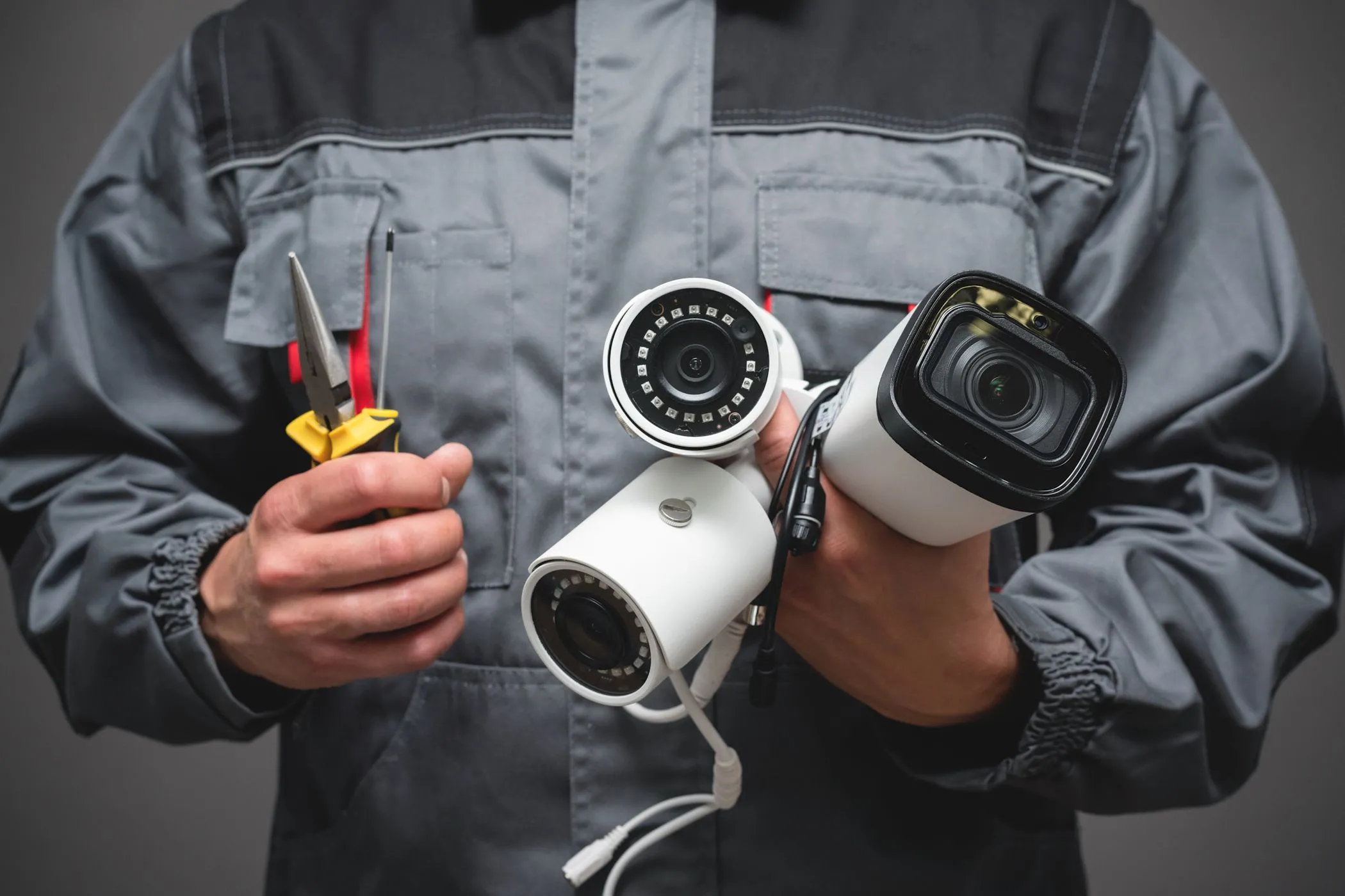 Người đàn ông cầm camera an ninh có dây, đại diện cho việc giám sát và quyền riêng tư