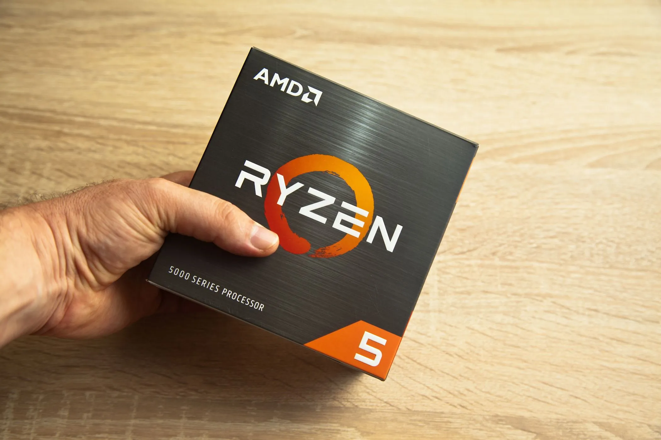 Người đàn ông cầm hộp bộ vi xử lý AMD Ryzen 5 series 5000, minh họa cho việc chọn CPU mạnh mẽ cho laptop giá rẻ.