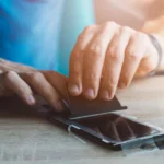 Người đàn ông đang dán miếng dán bảo vệ màn hình kháng khuẩn lên điện thoại iPhone
