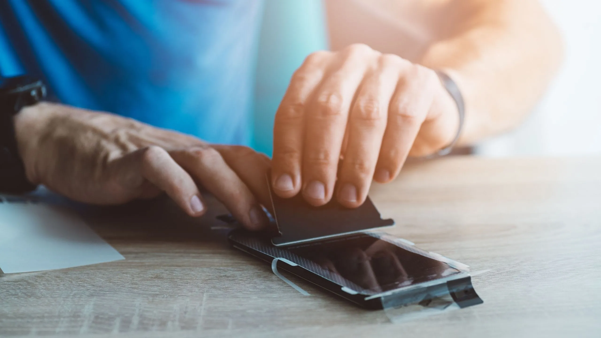 Người đàn ông đang dán miếng dán bảo vệ màn hình kháng khuẩn lên điện thoại iPhone
