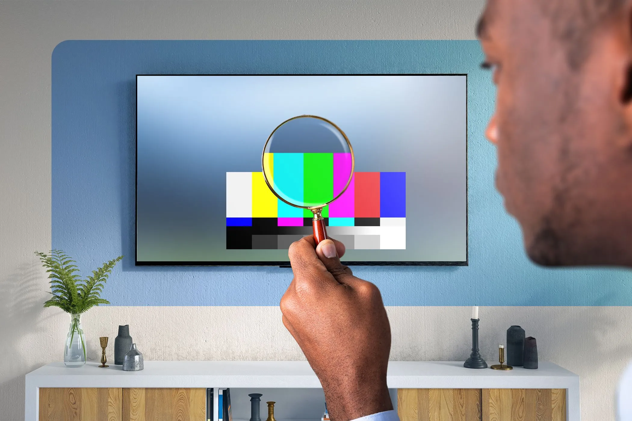 Người đàn ông đang kiểm tra chi tiết TV bằng kính lúp, tượng trưng cho việc tìm hiểu sâu về chất lượng hiển thị HDR