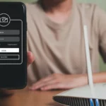 Người đàn ông đang kiểm tra điện thoại cạnh bộ định tuyến Wi-Fi, minh họa cho việc các thiết bị tìm kiếm mạng Wi-Fi, đặc biệt là mạng ẩn.