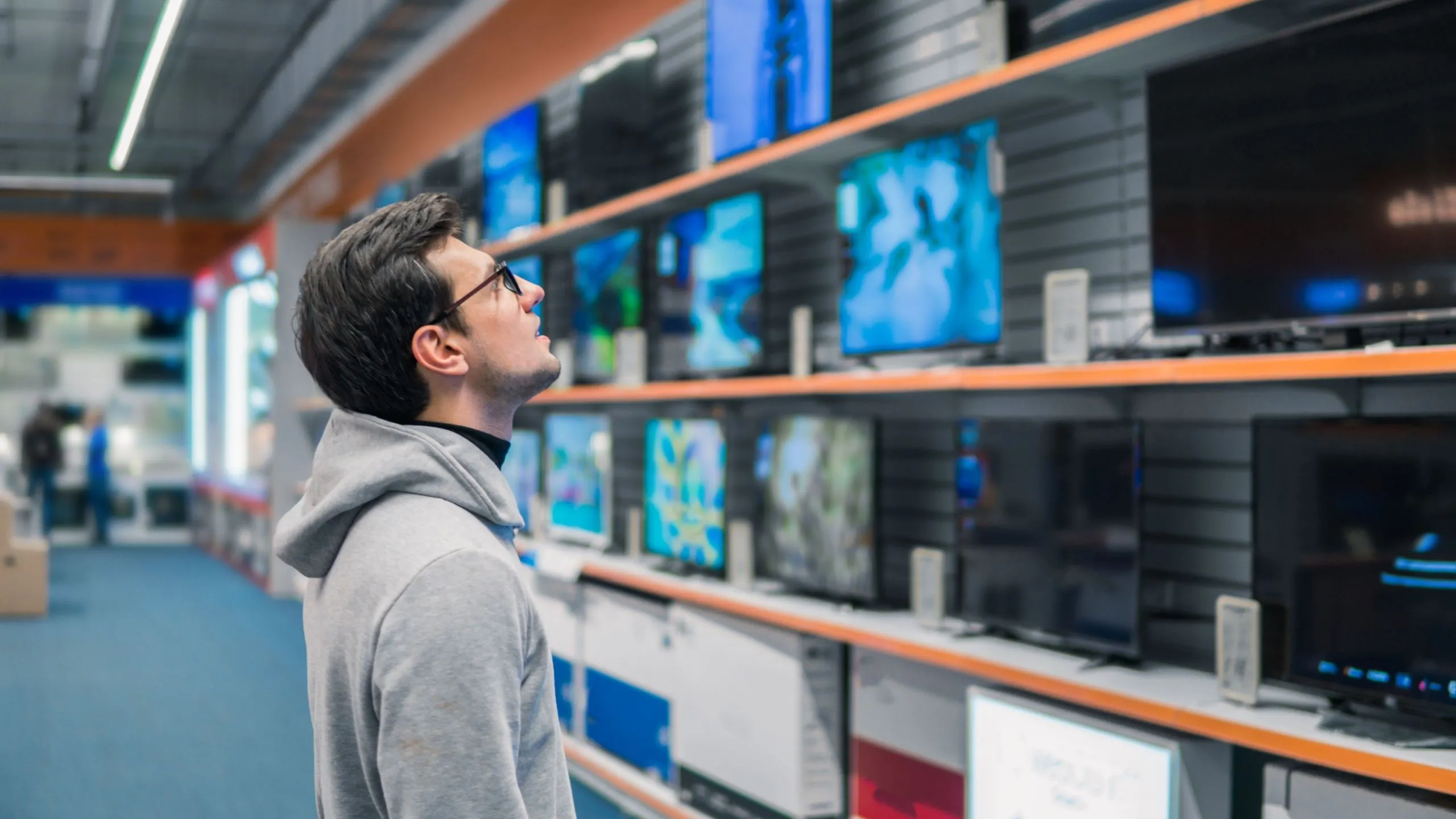 Người đàn ông đang xem xét các mẫu TV thông minh tại cửa hàng điện tử