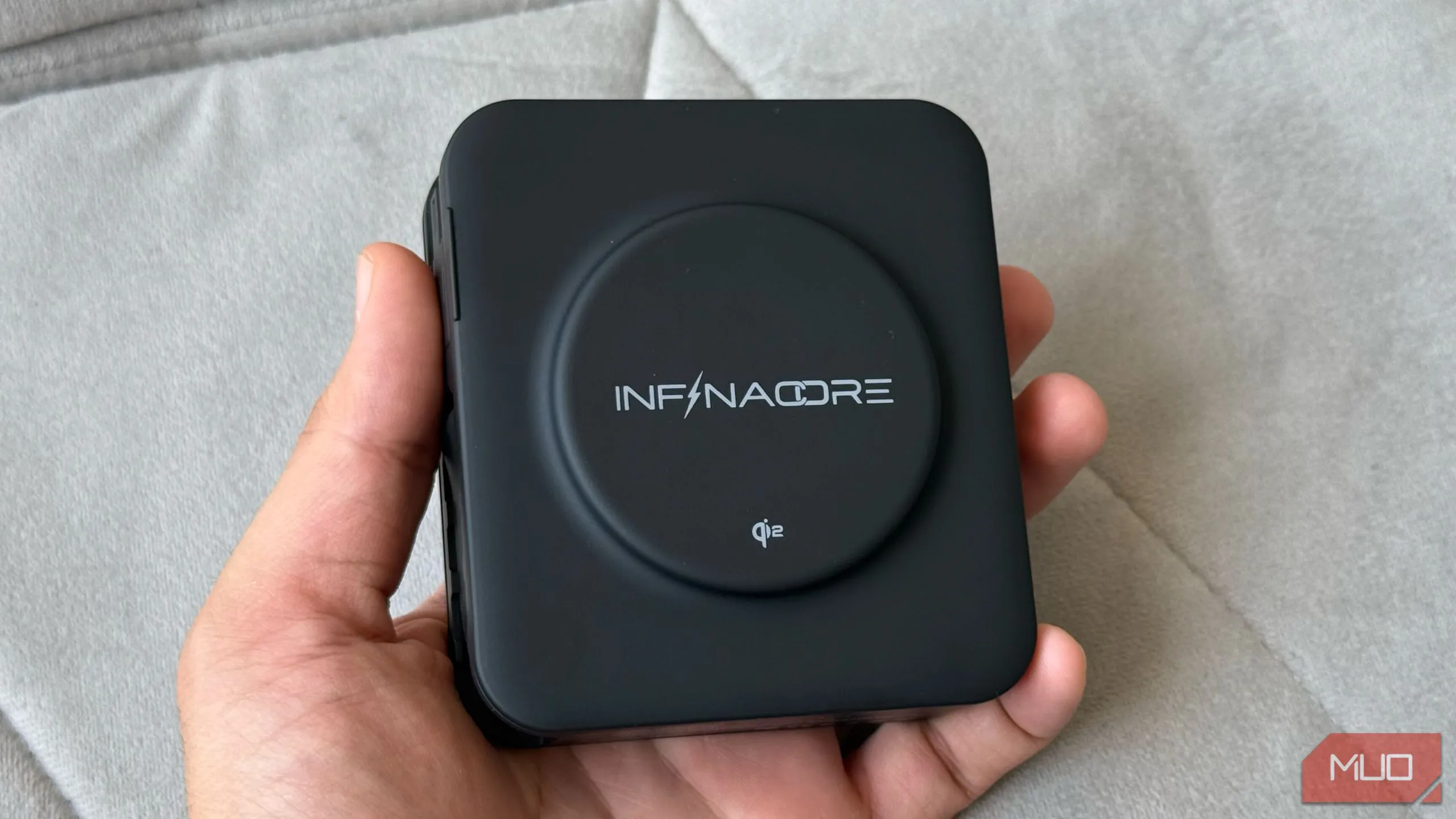 Người dùng cầm InfinaCore P3 Pro hiển thị phần sạc không dây Qi2