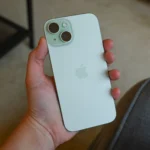 Người dùng đang cầm chiếc iPhone 15 màu xanh trên tay, minh họa thiết kế và kích thước thực tế của mẫu flagship năm trước.