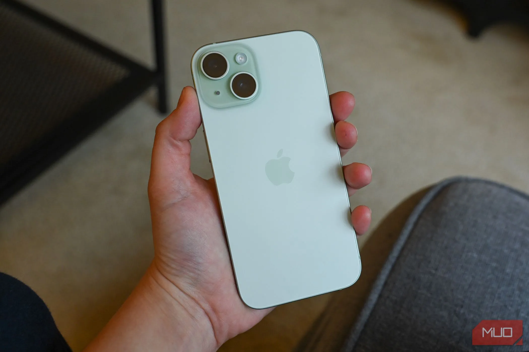 Người dùng đang cầm chiếc iPhone 15 màu xanh trên tay, minh họa thiết kế và kích thước thực tế của mẫu flagship năm trước.