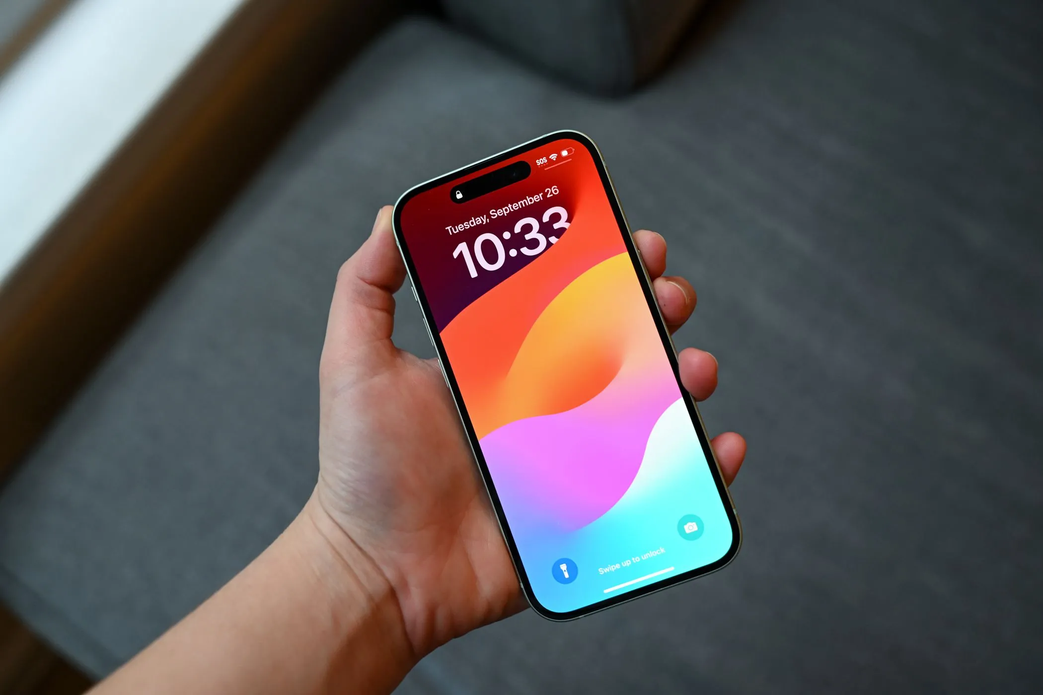 Người dùng đang cầm iPhone 15, màn hình có thể có vết xước nhỏ được che phủ bởi miếng dán bảo vệ