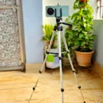 Người dùng đang gắn điện thoại lên chân máy (tripod) để chụp ảnh phong cảnh đêm đường phố, giúp ổn định máy và tránh rung mờ