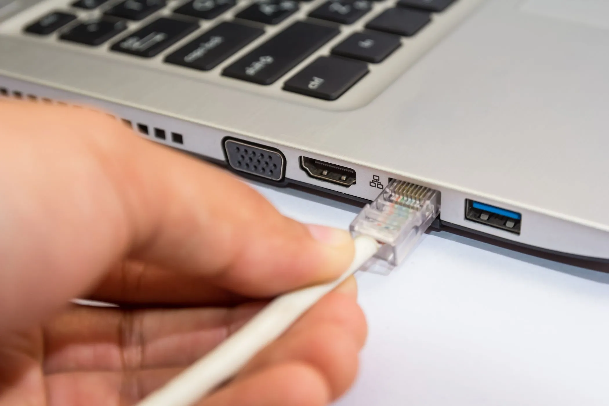 Người dùng kết nối cáp Ethernet vào laptop Windows để tăng bảo mật và tốc độ mạng