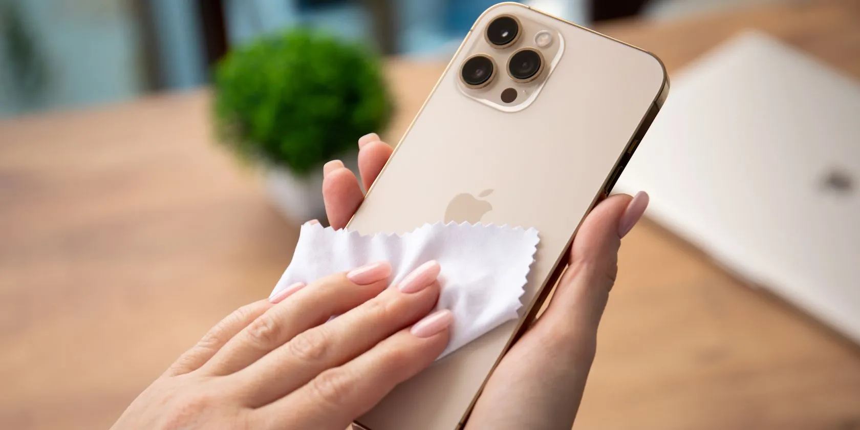 Người phụ nữ đang làm sạch màn hình iPhone bị bám vân tay bằng khăn microfiber chuyên dụng