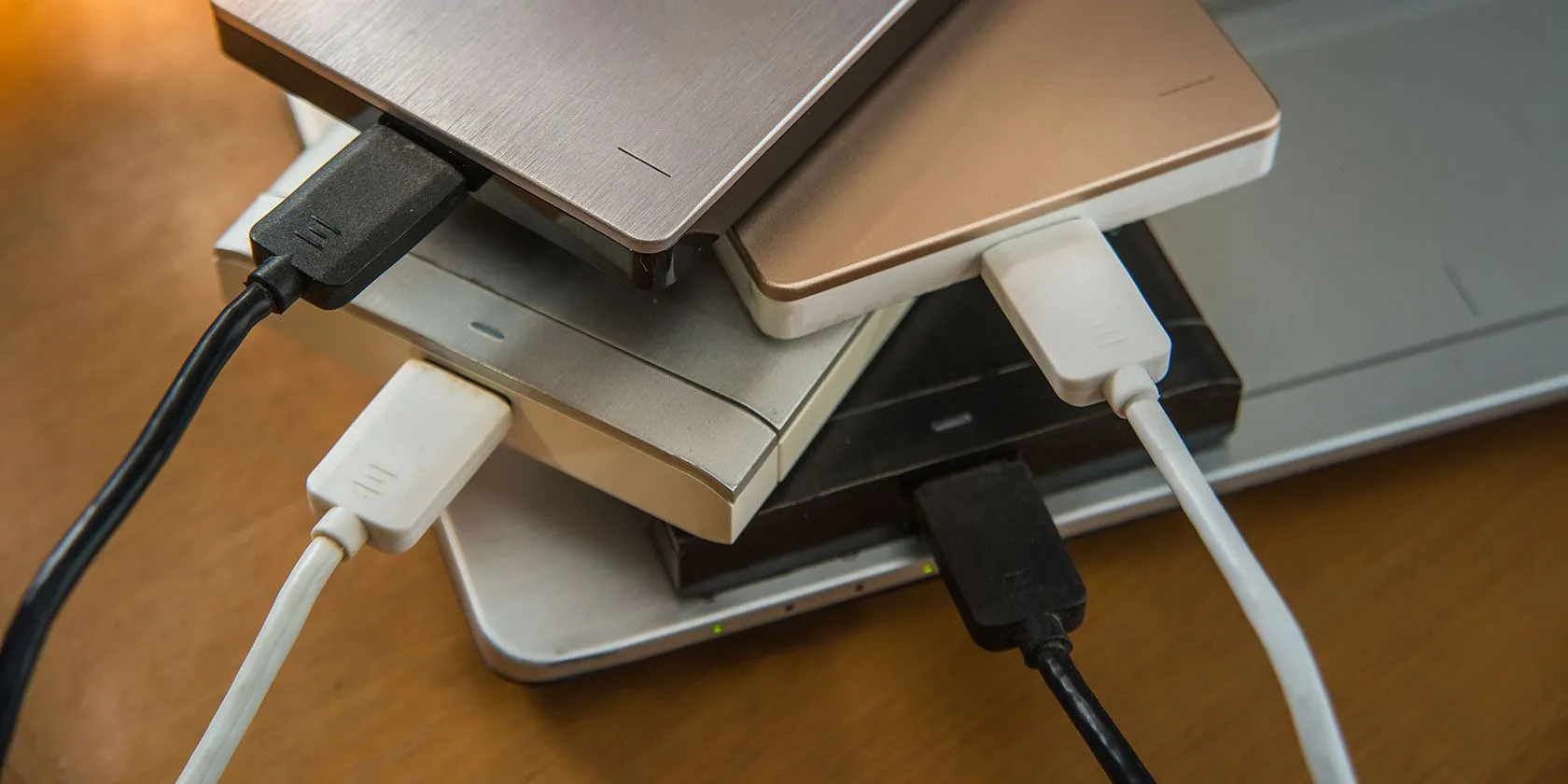 Nhiều ổ cứng di động và ổ cứng ngoài đặt cạnh laptop, minh họa sự phức tạp khi quản lý nhiều phân vùng.