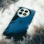 OnePlus 13 màu Midnight Ocean với mặt lưng da thuần chay, đặt trên thảm trắng mềm mại, tôn lên vẻ cao cấp.