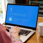 Phụ nữ đang nhìn màn hình laptop hiển thị lỗi màn hình xanh chết chóc (Blue Screen of Death) trên Windows, minh họa tình huống cần Live Linux USB cứu hộ.