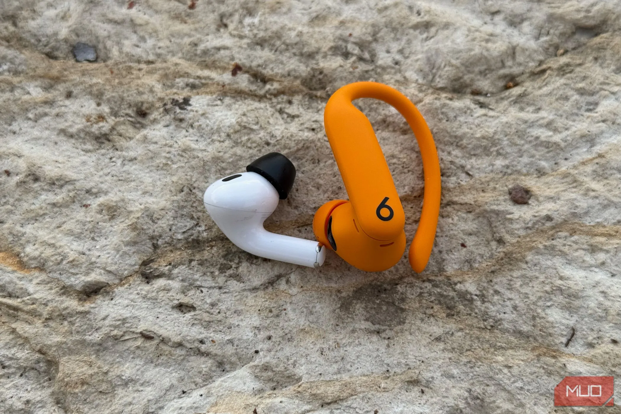 Tai nghe Apple AirPods Pro 2 và Powerbeats Pro 2 đặt cạnh nhau để so sánh kích thước và thiết kế.