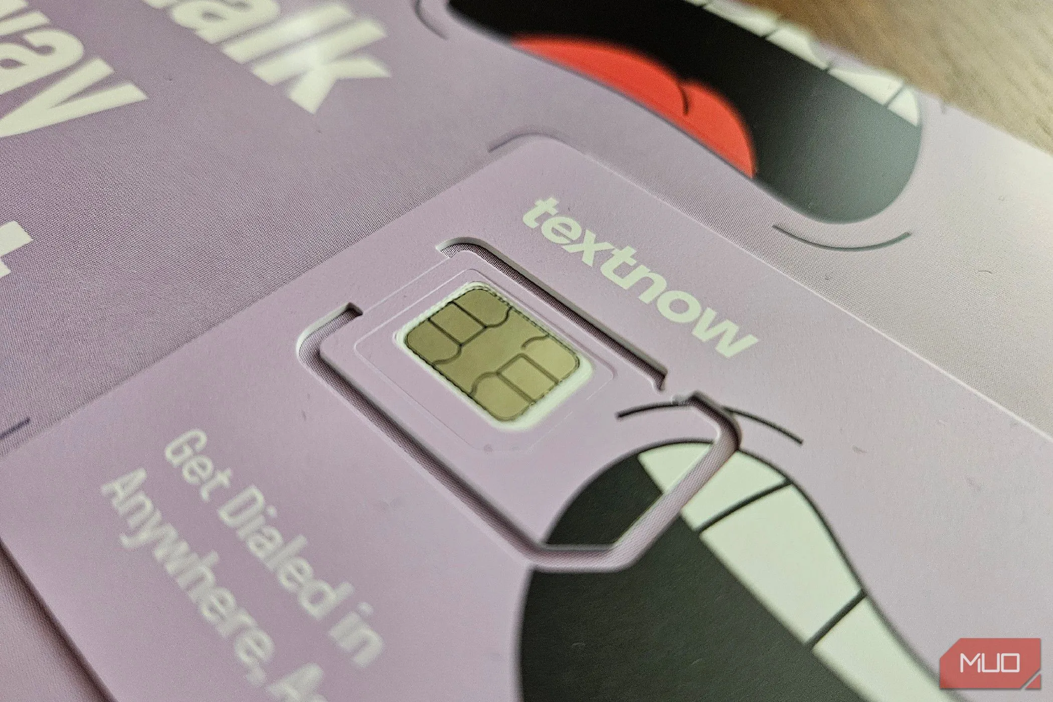 Thẻ SIM TextNow nằm trên bề mặt, tượng trưng cho sự phụ thuộc nhà mạng và kết nối di động.