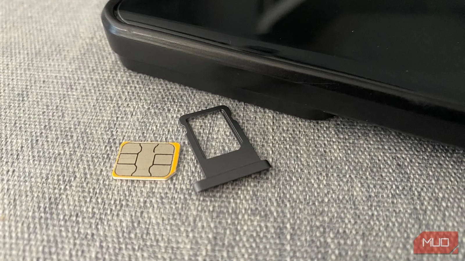 Thẻ SIM vật lý và khay đựng đặt cạnh điện thoại di động trên bàn, minh họa cho việc sử dụng SIM truyền thống.
