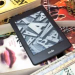 Thiết bị đọc sách Kindle đặt trên chồng sách vật lý, minh họa so sánh giữa eBook và sách in về quyền sở hữu