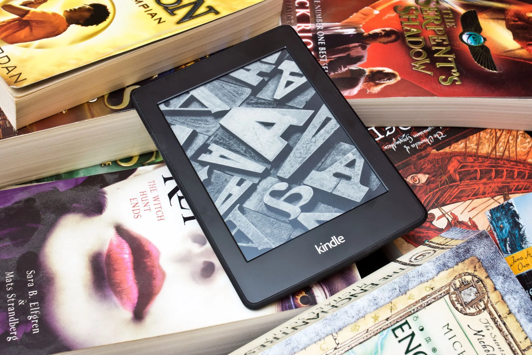 Thiết bị đọc sách Kindle đặt trên chồng sách vật lý, minh họa so sánh giữa eBook và sách in về quyền sở hữu