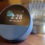 Thiết bị loa thông minh Amazon Echo Spot màu xanh đặt trên mặt gỗ với đèn bạc phía sau, minh họa cho việc xử lý dữ liệu Alexa.