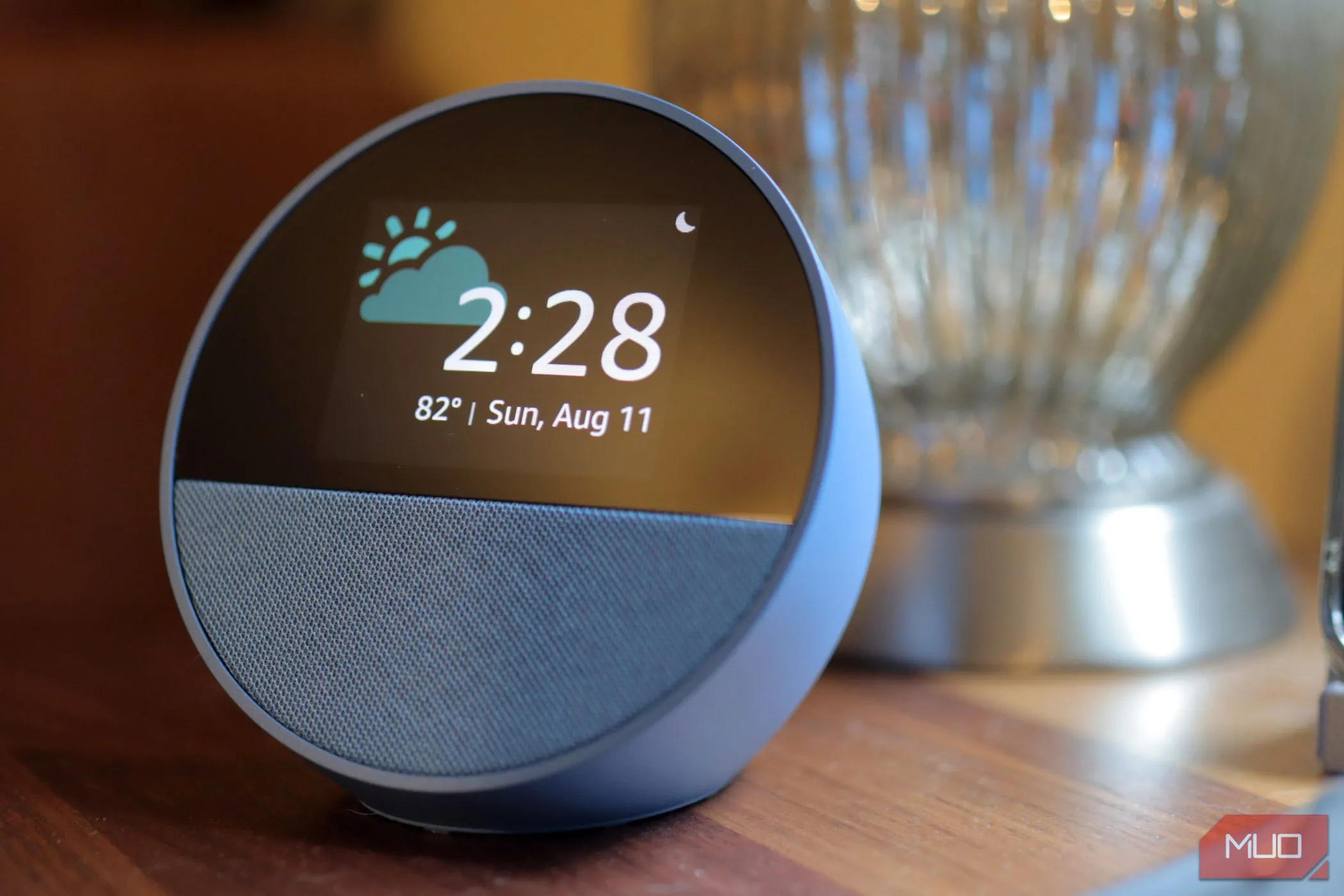 Thiết bị loa thông minh Amazon Echo Spot màu xanh đặt trên mặt gỗ với đèn bạc phía sau, minh họa cho việc xử lý dữ liệu Alexa.